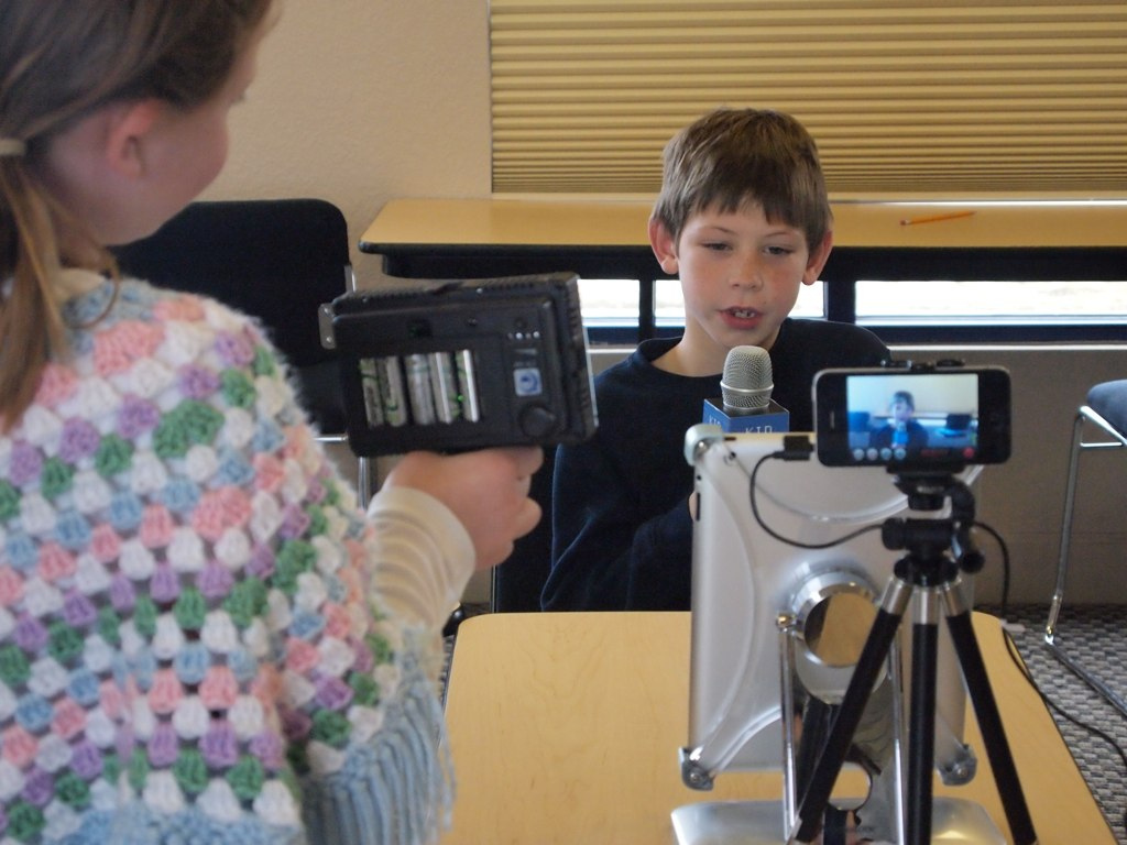 Elementary school students using iPads in a classroom, engaged in a media project